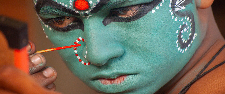 Kathakali performer doing his makeup