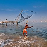 Fisherman throwing his net close to traditional chinese nets , Cochin, Kerala, South India