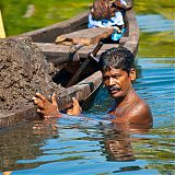 Diver bringing up mud for use in building works, Kerala Backwaters, South India
